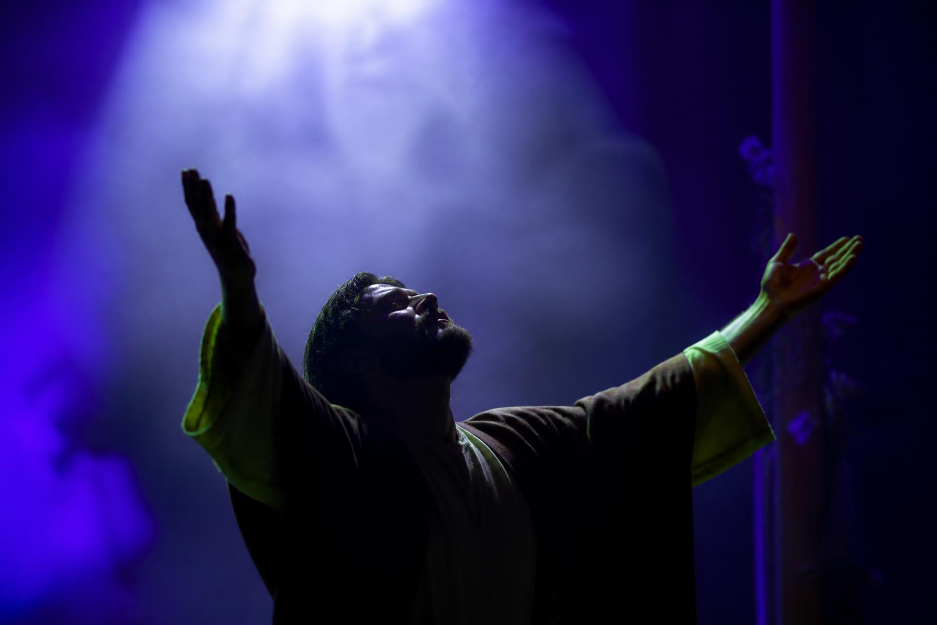 Ator cristão em palco de teatro com luz dramática